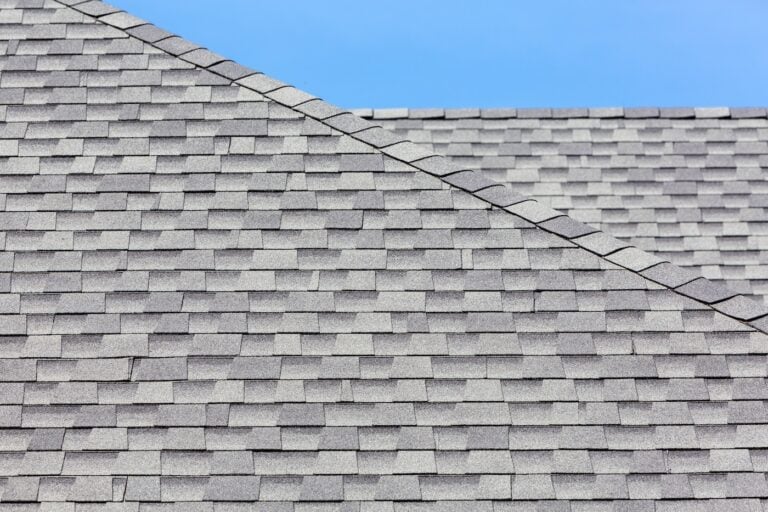 Close up of new asphalt roof tiles with blue skybackground.